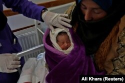 A trainee midwife examines a woman and her newborn baby at a hospital in Bamiyan.