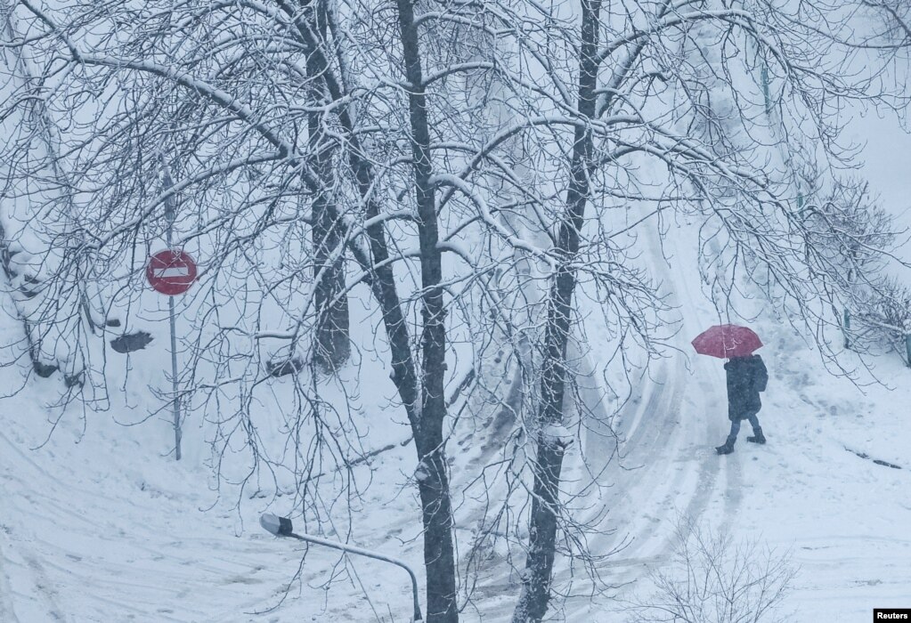 Një person me një çadër shihet duke ecur në rrugë në Kiev përderisa bie borë, mes sulmeve të Rusisë në Ukrainë, 1 dhjetor 2023.