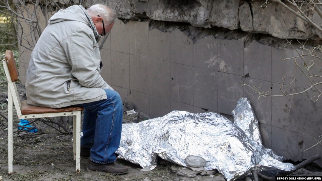 O rudă stă lângă cadavrul acoperit al unei tinere ucrainene care a fost ucisă într-un atac rusesc cu rachete asupra Kievului, pe 1 iunie.