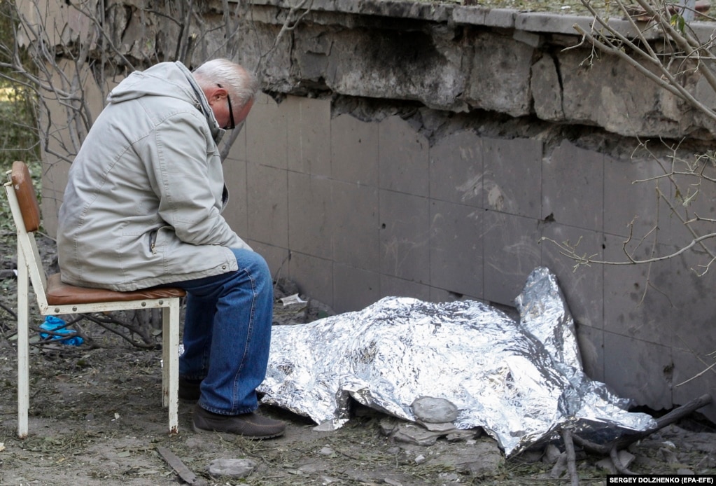 Një i afërm ulet pranë trupit të mbuluar të një vajze 9-vjeçare ukrainase, e cila u vra në një sulm me raketa ruse në Kiev.