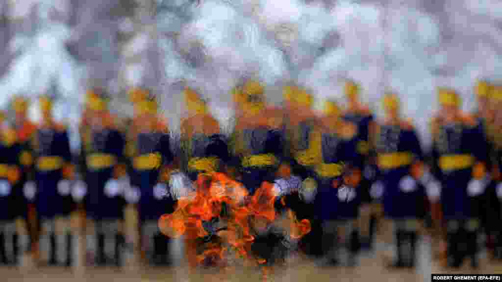 Vojnici rumunske predsjedničke počasne garde vide se kroz vječni plamen koji gori za poginule heroje dok odaju počast ispred Spomen-obilježja nepoznatom vojniku tokom vjerske ceremonije organizovane povodom obilježavanja 165. godišnjice ujedinjenja rumunskih kneževina u Bukureštu januara 24.