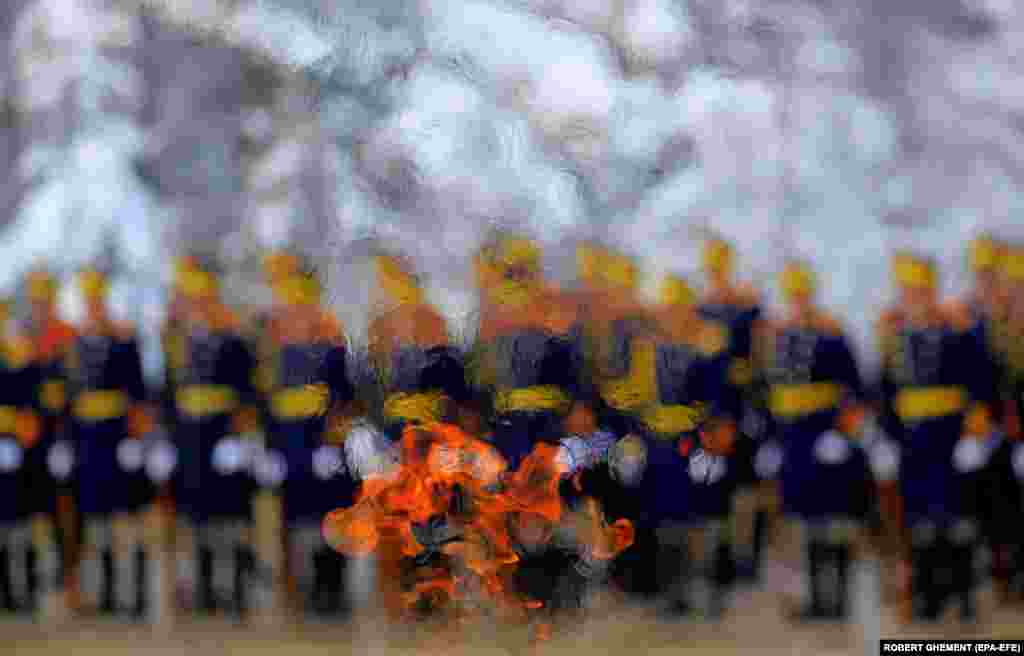 Soldiers of the Romanian Presidential Honor Guard are seen through the eternal flame that burns for fallen heroes as they pay their respects in front of the Unknown Soldier Memorial during a religious ceremony organized to mark the 165th anniversary of the Unification of the Romanian Principalities in Bucharest on January 24.