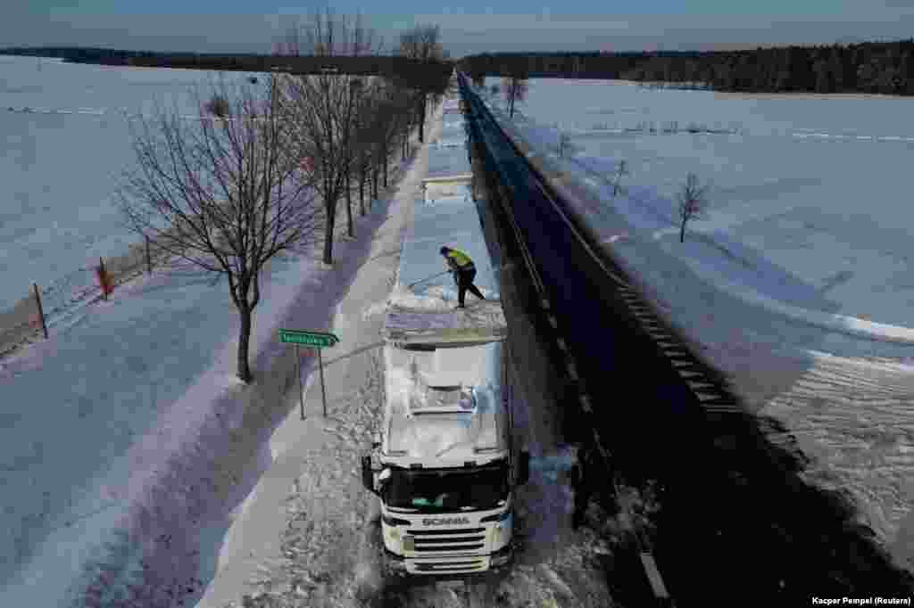 Vozač čisti snijeg s krova svog kamiona koji je zapeo u dugom redu za prijelaz poljsko-ukrajinske granice na prijelazu Hrebenne-Rawa Ruska u Potokiju u Poljskoj.