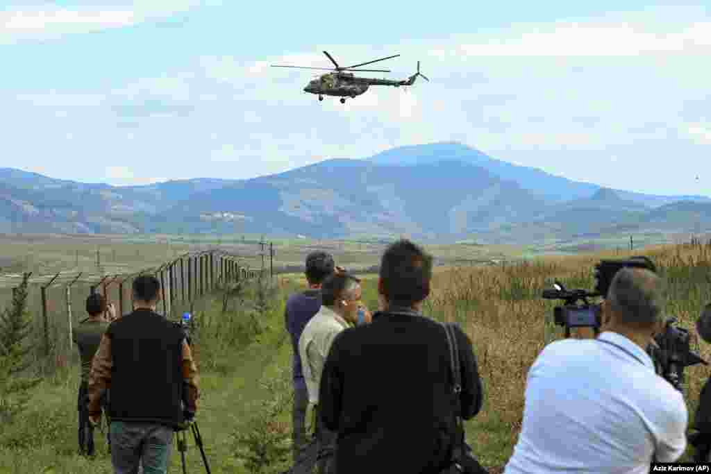 An international group of journalists film a Russian peacekeepers&#39; military helicopter as it flies over a field just outside Xankendi on October 2. Armenian authorities have accused the Russian peacekeepers who were deployed to Nagorno-Karabakh after the 2020 war of standing by and failing to stop the Azerbaijani onslaught. Moscow has rejected the accusations, arguing that its troops did not have a mandate to intervene.