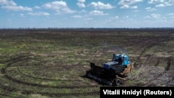 Созданная местным фермером на основе трактора машина с дистанционным управлением проводит разминирование близ села Граково в Харьковской области, 26 апреля 2023 года