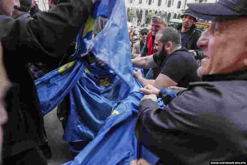 Supporters of the Conservative Movement and the pro-Russian platform Alt-Info rip an EU flag during a rally in front of the parliament building in Tbilisi.