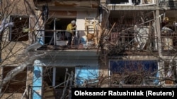 Місцева жителька прибирає свою квартиру в житловому будинку, пошкодженому під час російського військового удару у місті Курахове Донецької області, Україна, 4 березня 2024 року