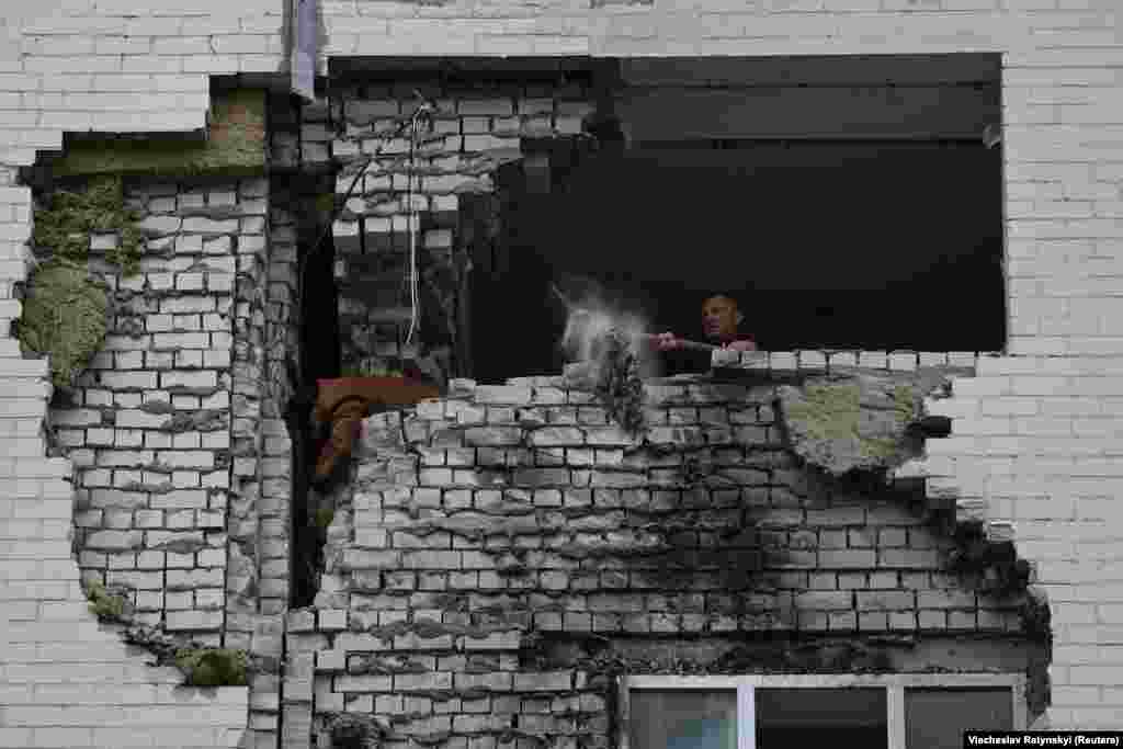 A local man clears the wreckage from his flat after it was struck by Russian missile fragments. &nbsp;