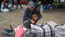 Muškarac drži psa dok stanovnici Vovčanska i obližnjih sela u Harkivskoj oblasti čekaju autobuse kako bi se evakuisali usled ruske invazije na tu oblast u Ukrajini, 12. maj 2024.