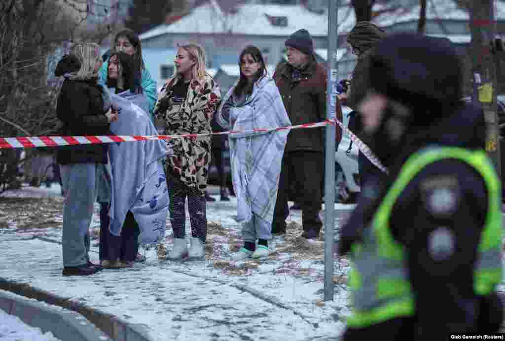 Residents stand in the freezing temperatures near the site of their damaged apartment building. The attack injured at least 20 people in four districts of Kyiv, the capital, including a 13-year-old boy, according to Mayor Vitali Klitschko.