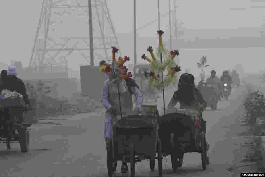 Corn sellers push their handcarts as smog envelops Lahore, Pakistan.