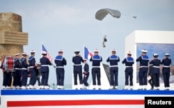 Парашутист прибуває під час гри музикантів французького флоту в Омаха-Біч з нагоди 80-ї річниці висадки союзників в Нормандії. Франція, 6 червня 2024 року