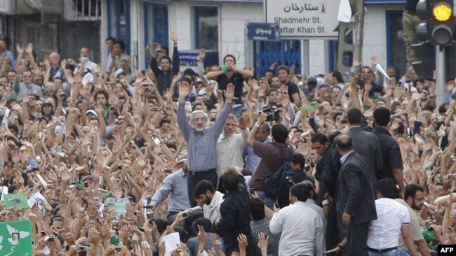 Mir Hossein Musavi (C) raises his arms as he appears at an opposition protest in Tehran, 15Jun2009