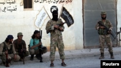 Syrian rebel fighters pose near Islamic State calligraphy and drawings in Dabiq after capturing the city on October 16.