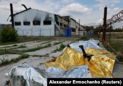 Обгорілі тіла ув'язнених накриті після вибуху у колонії в селищі Оленівка Донецької області, Україна, 29 липня 2022. REUTERS