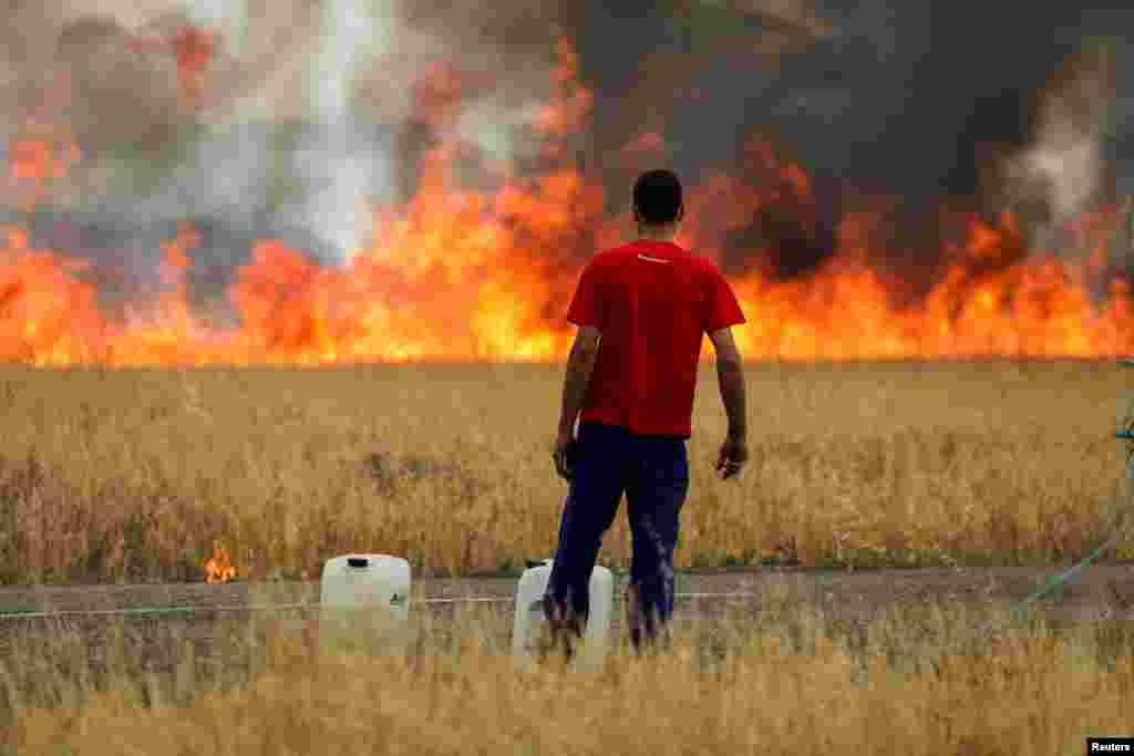 Un cioban privește un incendiu de vegetație de pe un câmp de grâu între Tabara și Losacio, în provincia Zamora, Spania, 18 iulie 2022.&nbsp;Acesta este al doilea val de căldură care afectează peninsula iberică în acest an.