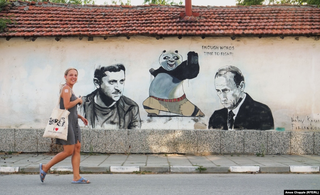 Anna Kossyk duke kaluar pranë një muri që ajo dhe studentë të tjerë polakë të artit e pikturuan në vitin 2022.