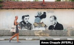 Anna Kossyk duke kaluar pranë një muri që ajo dhe studentë të tjerë polakë të artit e pikturuan në vitin 2022.