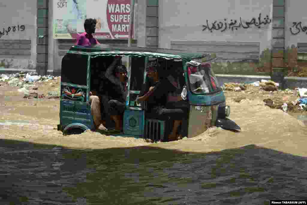Commuters travel on a flooded road after heavy rain in Karachi, Pakistan, on July 11.