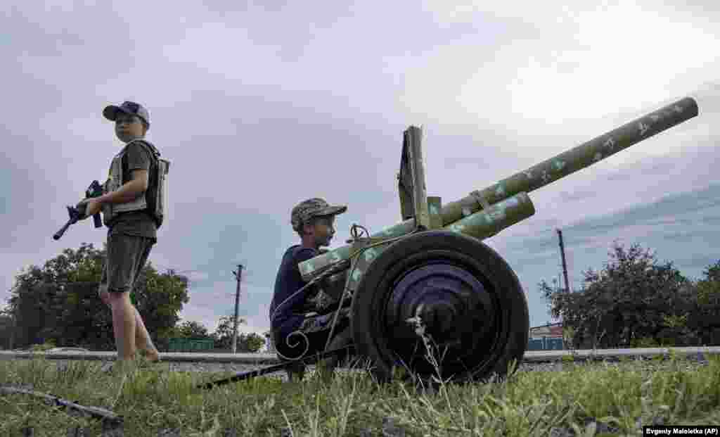 Maksym and Andriy play with a homemade &quot;howitzer&quot; on a highway in the Kharkiv region on July 20.&nbsp;