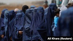 Афганские женщины стоят в ожидании денежной помощи для перемещенных лиц в Кабуле, Афганистан, 28 июля 2022 года.