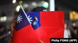 Muškarac drži tajvanske zastave na obilježavanju Tajvanskog nacionalnog dana u Hong Kongu 10. oktobra 2019. Tajvanski nacionalni dan, koji se takođe naziva Double-Ten, slavi se u sećanje na ustanak iz 1911. koji je okončao poslednju kinesku carsku dinastiju i uveo Republiku Kinu.
