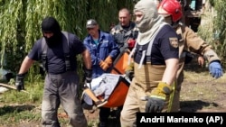 Rescuers remove the body of a woman killed by a Russian missile attack in Chuhuiv, in Ukraine's Kharkiv region, on July 26.