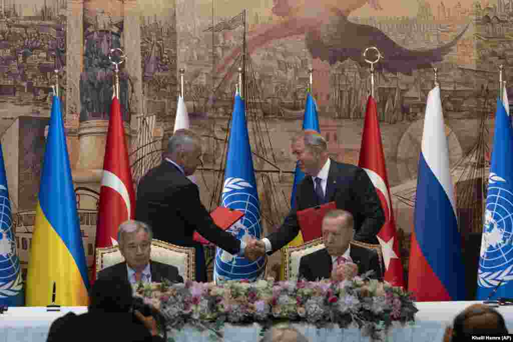 Ministrul rus al Apărării, Serghei Shoigu, și cel al Turciei, Hulusi Akar, își strâng mâinile în timpul ceremoniei la Palatul Dolmabahce din Istanbul, Turcia, vineri, 22 iulie 2022. Secretarul general al ONU, Antonio Guterres, în dreapta,&nbsp;și președintele Turciei, Recep Tayyip Erdoğan, au supervizat semnarea acordului-cheie care ar permite Ucrainei să reia&nbsp;transportul de cereale din Marea Neagră către piețele mondiale și Rusiei să exporte cereale și îngrășăminte, punând capăt unui impas care amenință securitatea alimentară mondială.