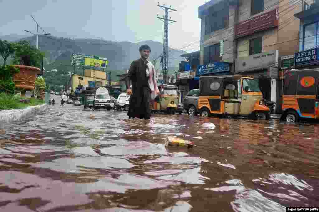 A man wades across a flooded street amid monsoon rains in Muzaffarabad, the capital of Pakistan-administered Kashmir.