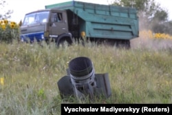 Földbe fúródott rakétaelem egy búzával megrakott teherautóval a háttérben Harkivban 2022. július 30-án