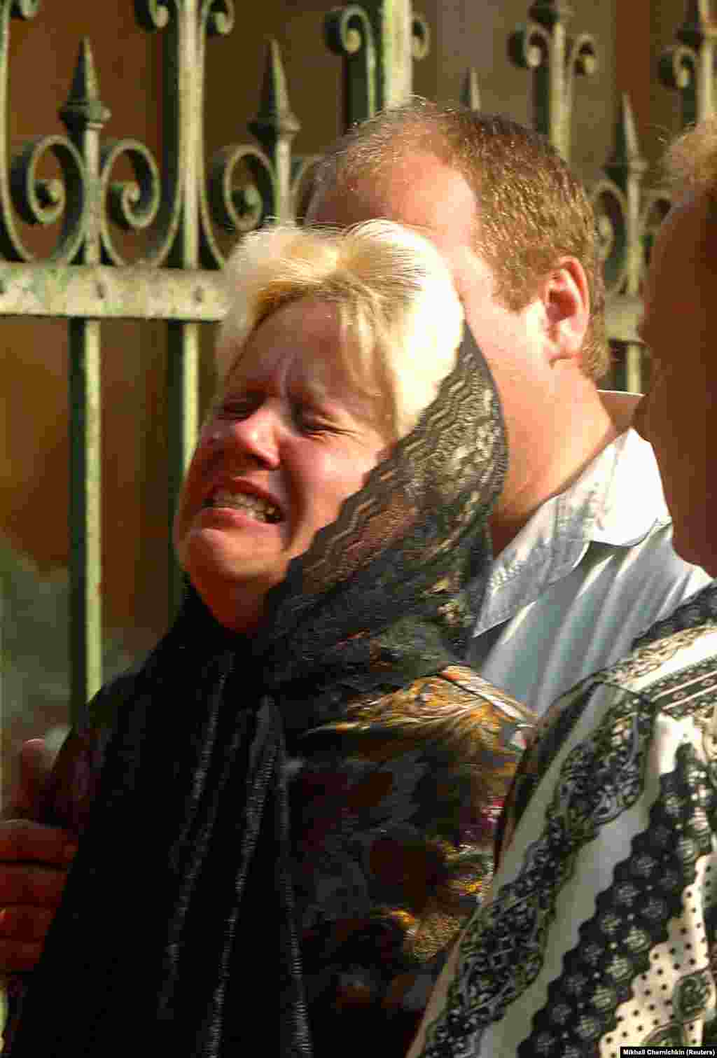 A mother sobs as she waits to identify the bodies of her two children who died during the air show tragedy a day earlier. The process of identifying the bodies was especially difficult due to the horrific damage inflicted.