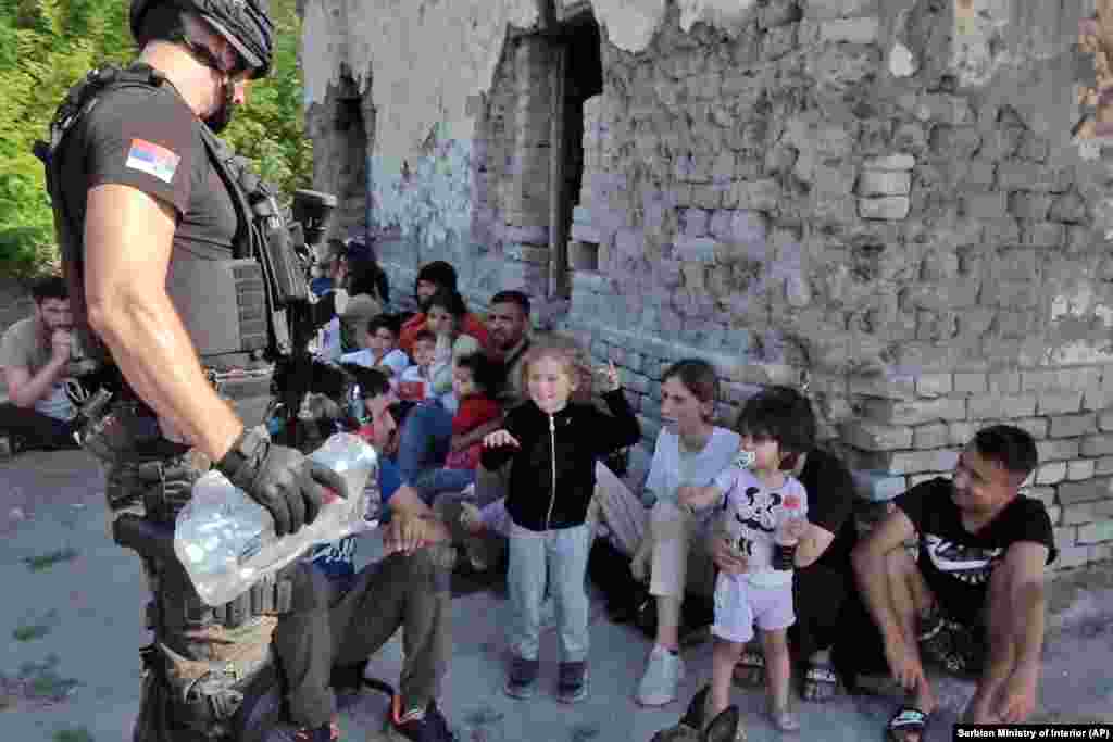 In a photo provided by the Serbian Interior Ministry, a police officer gives water to migrant children near the village of Horgos.