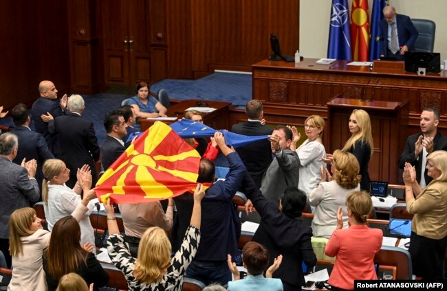 Депутати в македонския парламент развяват знамената на Северна Македония и на ЕС след гласуването в подкрепа на френското предложение. Снимката е от 16 юли