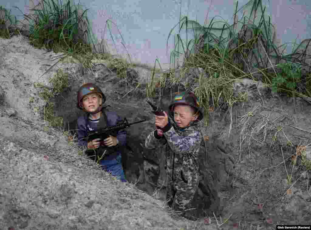 Andriy, 12, and Valentyn, 6, play in a foxhole dug near their homes in Stoyanka on May 22.&nbsp;