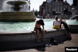 Londoniak küzdenek a kánikulával a Trafalgar tér szökőkútjánál 2022. július 19-én