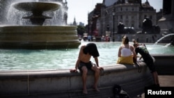 Ljudi se rashlađuju pored fontane na Trgu Trafalgar u Londonu, 19. juli 2022. 
