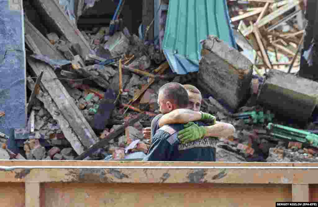 Rescuers react near the body of a person who was removed from the debris of a social and cultural center that hit by Russian shelling in the city of Chuhuiv, Ukraine.