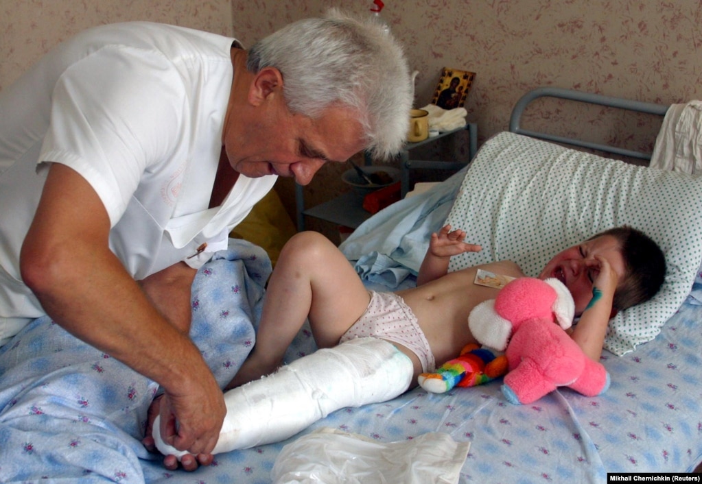 Voldya, shtatë vjeçe, i cili u lëndua në katastrofën e shfaqjes ajrore, shihet duke qarë ndërsa kirurgu Ivan Fedorko, trajton këmbën e tij në një spital fëmijësh në Lviv më 28 korrik 2002.