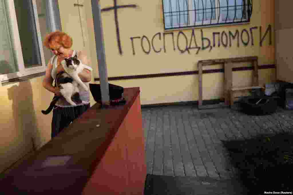 Natalya carries the family cat downstairs past graffiti that reads &quot;Lord, help us&quot; to their cellar. Regarding the future, the family has no answers, only questions, said 62-year-old Fedor. &quot;When will this war end? And on whom does it depend? On politicians? On us? On the military? Because it is unacceptable in our time, it is savagery that my mother-in-law and other old people who are 95 or 97 years old should end their lives in such conditions. The sooner it ends, the better.&quot; &nbsp;