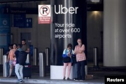 Udhëtarët duke pritur pranë sinjalistikës së ndarjes së udhëtimit në Uber, pasi kanë mbërritur në Aeroportin Ndërkombëtar të Los Angelesit (LAX), Kaliforni, SHBA, 10 korrik 2022.
