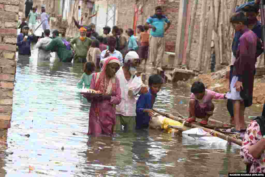 People affected by monsoon rains receive free food distributed by an aid group in Hyderabad, Pakistan. Heavy rains have claimed 310 lives so far in Pakistan during the current monsoon season.