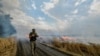 A Ukrainian fighter walks past a burning wheat field in eastern Ukraine&nbsp;near the front lines of the Russian advance on July 17.