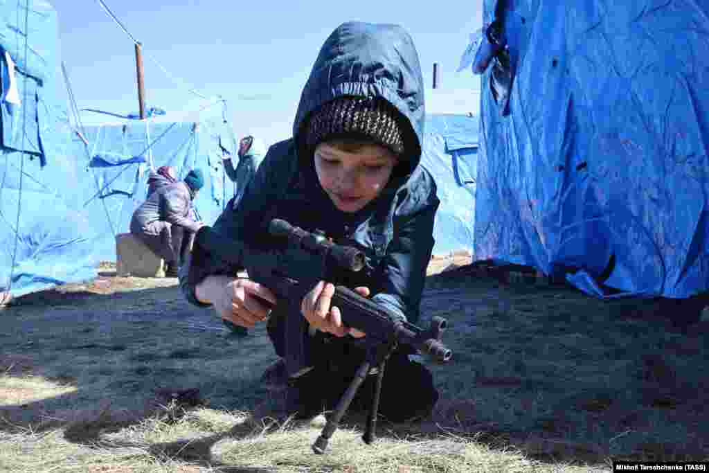 A boy plays with his plastic rifle at a tent camp for evacuated civilians in the Donetsk region on March 24.&nbsp;