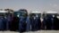 Displaced Afghan women wait to receive cash aid for displaced people in Kabul.