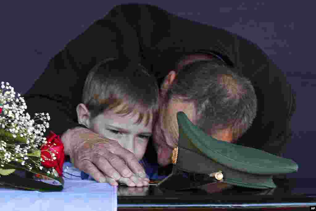The father and son of Russian Army Sergeant Daniil Dumenko, who was killed during fighting in Ukraine, mourn at his funeral in Volzhsky, near Volgograd, Russia, on May 26.&nbsp;