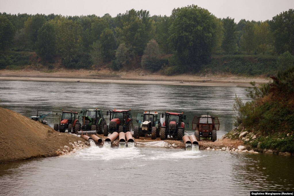 Traktorët e pajisur me pompa duke nxjerrë ujë nga lumi Po, në një kanal ujitjeje, më 22 qershor. Poja është lumi më i gjatë i Italisë dhe i furnizon me ujë disa prej rajoneve më të njohura për prodhim të ushqimit në Itali.