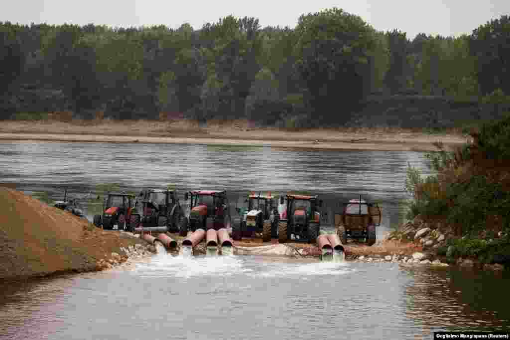 Tractoare echipate cu pompe trag apa din Po într-un canal de irigații pe 22 iunie. Fluviul Po este cea mai lungă apă curgătoare din Italia și alimentează cu apă unele dintre cele mai emblematice regiuni italiene producătoare de alimente.