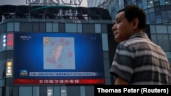 Čovek stoji ispred ekrana na kom se prikazuju vesti o vojnim vežbama u blizini Tajvana u Pekingu, 3. avgust 2022. 