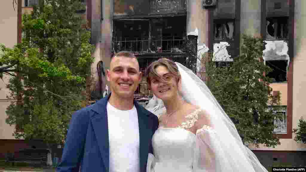 Mihajlo és Anasztaszia esküvői fotója egy kiégett épület előtt, miután összeházasodtak a Kijev melletti Bucsában május 26-án. A közhivatalokat Irpinyben és Bucsában&nbsp;májusban nyitották meg újra, amikor az orosz csapatok visszavonultak Kijev mellől