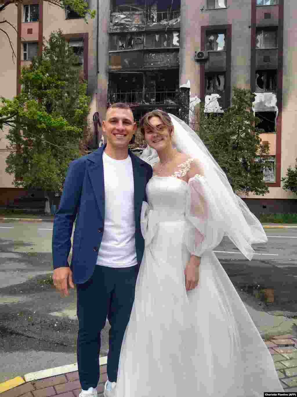 Mykhaylo and Anastasia Dewberry pose in front of a damaged building after being married in Bucha, near Kyiv, on May 26. Wedding offices in Bucha and the nearby town of Irpin were reopened in May after Russian troops abandoned their advance on Kyiv. &nbsp;